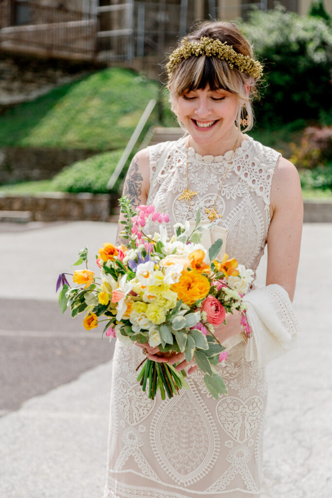 Bride admiring her colorful spring wedding bouquet before an intimate church ceremony