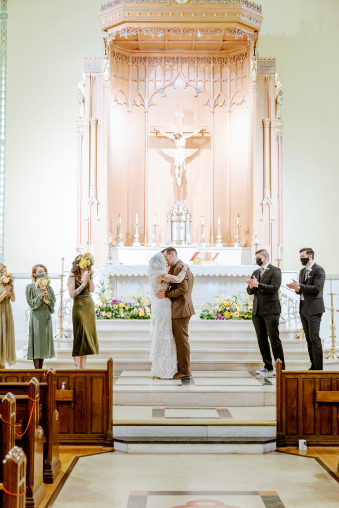 Bride and groom share their first kiss during an intimate church wedding ceremony in Philadelphia