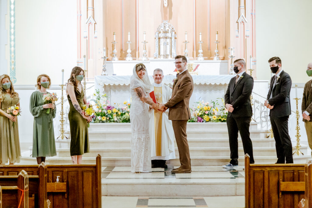 Bride and groom smiling at their wedding guests during a spring wedding ceremony