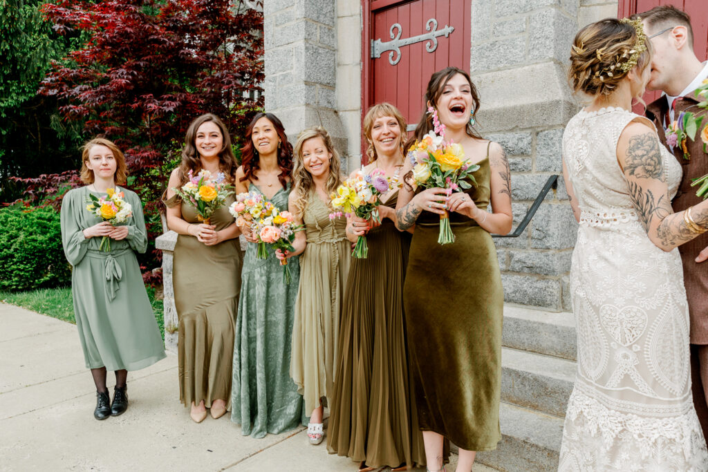 Bridesmaids cheer as the bride and groom kiss outside the church