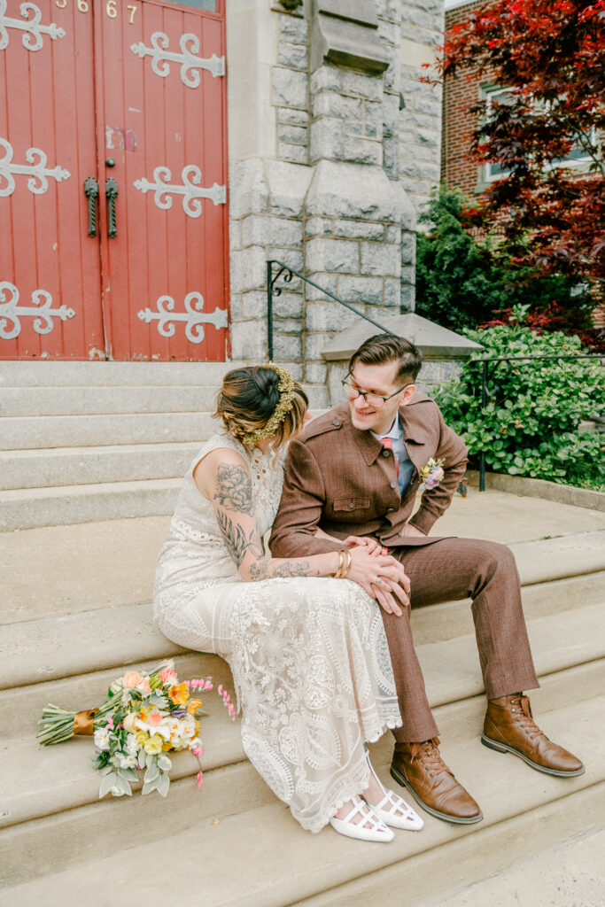 Bride and groom sitting on the church steps on a spring day in East Falls by photographer Vay Photo