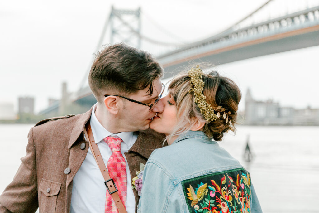 Philly bride and groom kissing in front of the Ben Franklin Bridge by Vay Photo