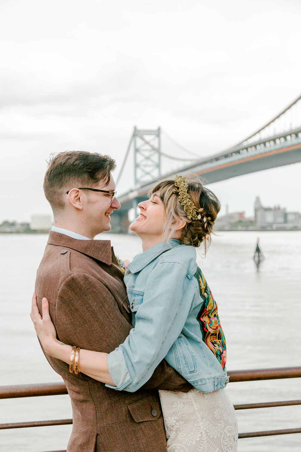 Philadelphia newlyweds smiling in front of the Ben Franklin Bridge on a spring wedding day