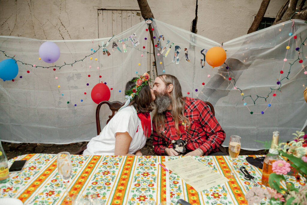 Newlyweds share their first kiss during a small summer backyard wedding by Vay Photo